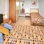 Hotelzimmer mit zwei Betten und bunter Bettwäsche.