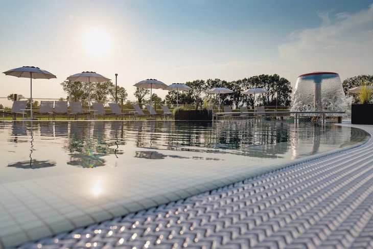 Außenpool mit Sonnenschirmen im Marina Azzurra Resort bei Sonnenuntergang.