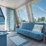 Wohnbereich mit türkisblauem Sofa, großem Fenster und moderner Einrichtung.