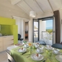 Essbereich in Ferienwohnung mit gedecktem Frühstückstisch, Küchenecke und Balkonblick.