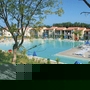 Blick auf einen Pool in einer Ferienanlage mit Liegestühlen und Sonnenschirmen.