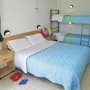 Doppelbett und Etagenbett in hellem Apartment mit blauen Akzenten.