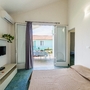 Innenraum eines hellen Schlafzimmers mit Zugang zur Terrasse und Sonnenblumenbild an der Wand.