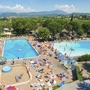 Luftaufnahme von zwei Pools und vielen Menschen auf einem Campingplatz bei Sonnenschein.