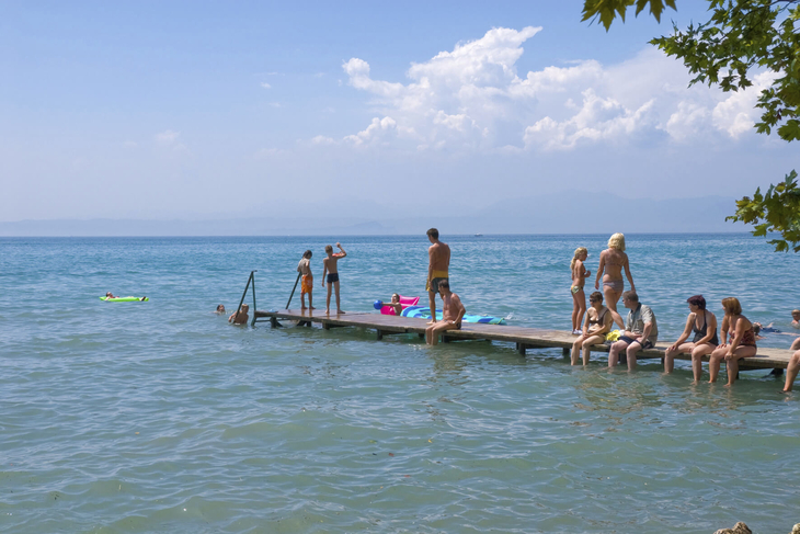Menschen auf einem Steg am See genießen das sonnige Wetter.