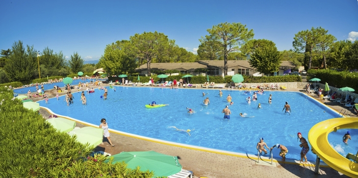 Menschen entspannen und schwimmen in einem großen, sonnigen Pool in einem Campingplatz.