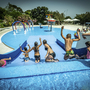 Kinder spielen auf einer Wasserrutsche in einem Pool unter freiem Himmel.