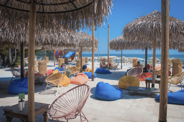 Entspannungsbereich mit Strandkörben und Sonnenschirmen aus Stroh am Strand.