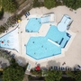 Luftaufnahme eines großen Pools mit Sonnenliegen und Bäumen im Happy Camp San Francesco.