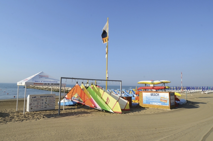 Bunte Strandboote und Liegen am Sandstrand mit klarem Himmel.