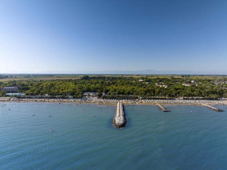Luftaufnahme eines Strandes mit Pier und umliegendem Grünland.