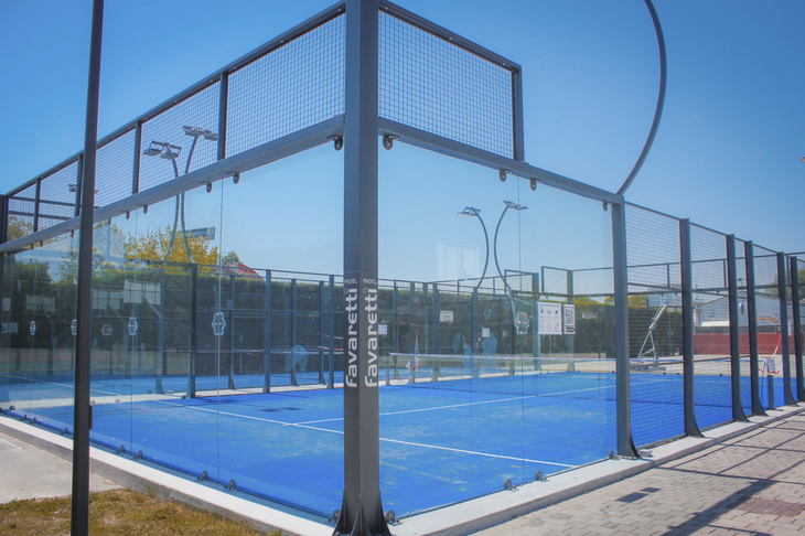 Padelplatz im Freien mit blauen Spielfeldern und Glaswänden bei Sonnenschein