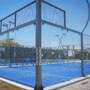 Padelplatz im Freien mit blauen Spielfeldern und Glaswänden bei Sonnenschein