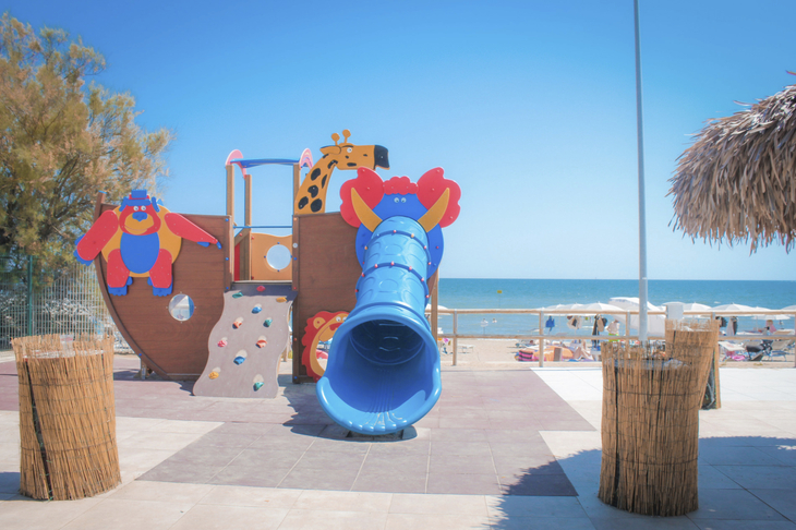 Spielplatz mit bunter Rutsche am Strand bei sonnigem Wetter.