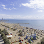 Strand mit Sonnenschirmen, Spielplatz und Leuchtturm im Hintergrund.