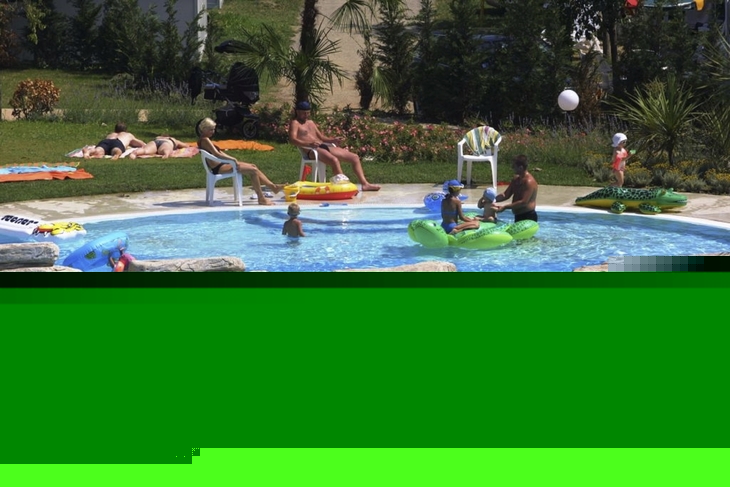 Menschen entspannen und spielen im Pool eines Campingplatzes mit Liegestühlen und Spielzeugen.