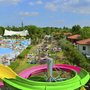 Feriendorf mit Pool, grüner Landschaft und bunter Rutsche auf Campingplatz.
