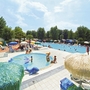 Blick auf einen belebten Campingplatz mit Pools und Sonnenschirmen.