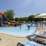 Kinder spielen im Pool mit Rutsche auf einem Campingplatz bei Sonnenschein.