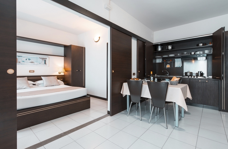 Wohnbereich mit Esstisch, Küche und Schlafzimmer in einem Apartment.