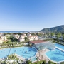 Panoramablick auf Pools und Gebäude im Loano 2 Village, Berge im Hintergrund.