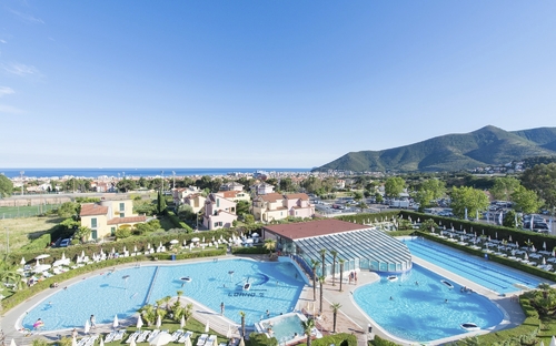 Panoramablick auf Pools und Gebäude im Loano 2 Village, Berge im Hintergrund.