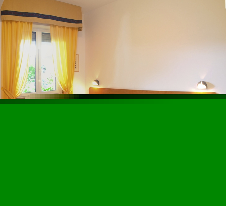 Hotelzimmer mit Doppelbett, gelben Vorhängen und Nachttischen.