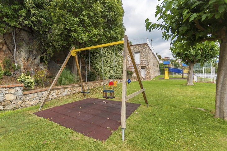 Spielplatz mit Schaukel und Rutsche in einer grünen Gartenanlage