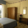 Schlafzimmer mit Doppelbett, Kleiderschrank, Fenster und Nachttischlampe.