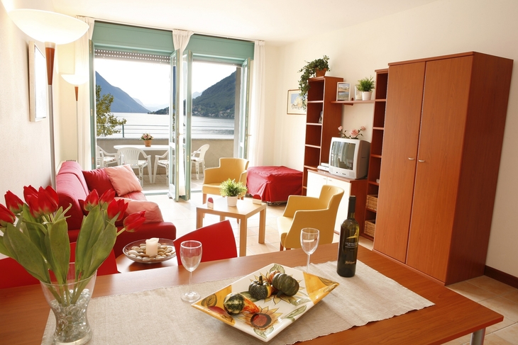 Wohnzimmer in Ferienwohnung mit Seeblick, Esstisch, Sofa und Fernseher.