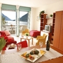 Wohnzimmer in Ferienwohnung mit Seeblick, Esstisch, Sofa und Fernseher.