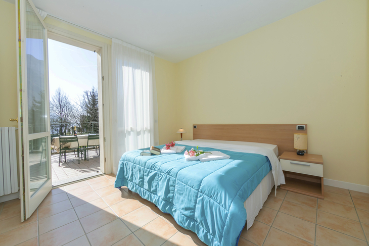 Schlafzimmer mit Doppelbett, Terrasse und gelben Wänden im ersten Stock einer Villa.