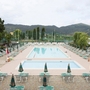 Zwei Swimmingpools in einer Ferienanlage mit Liegestühlen und Sonnenschirmen.