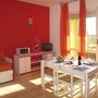 Helles Wohnzimmer mit roter Wand, Esstisch, Sofa und Balkon mit Vorhängen.