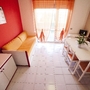 Wohnzimmer mit roter Wand, Sofa, Esstisch und großer Fensterfront.