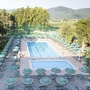 Swimmingpool mit Liegestühlen und Sonnenschirmen in einer grünen Umgebung.