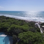 Blick auf bewaldeten Küstenbereich mit Strand und Meer im Hintergrund.
