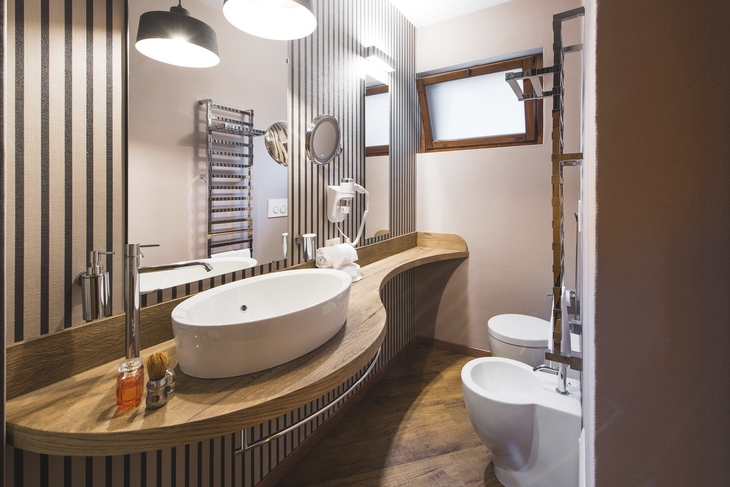 Modernes Badezimmer mit ovalem Waschbecken, Holztheke und Duschkabine.