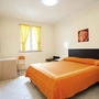 Zimmer mit orangefarbenem Bett und gelben Vorhängen.