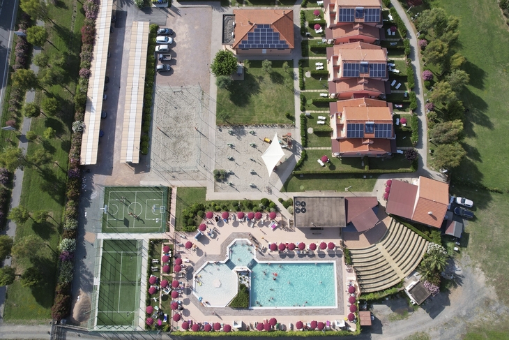 Luftaufnahme eines Resorts mit Pool, Volleyballfeld, Häusern und Tennisplatz.