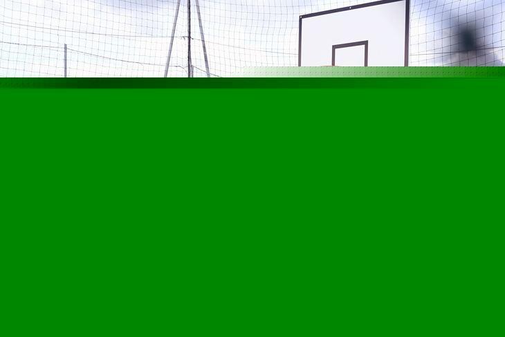 Basketballplatz mit Korb und umliegenden Gebäuden im Hintergrund.