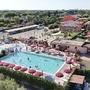 Luftaufnahme eines Freibades mit roten Sonnenschirmen und umliegenden Gebäuden.