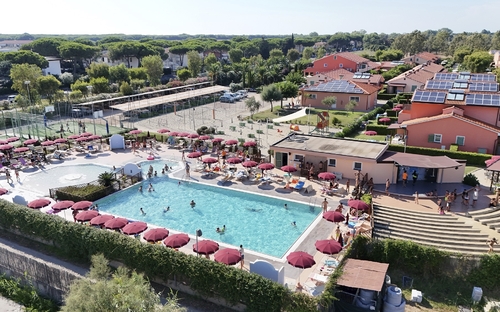Luftaufnahme eines Freibades mit roten Sonnenschirmen und umliegenden Gebäuden.