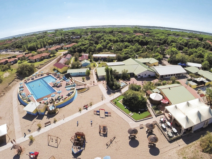 Luftaufnahme eines Ferienclubs mit Pool, Gebäuden und umgebender Landschaft.