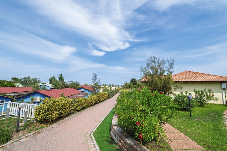Gartenweg mit Häusern und blauem Himmel in Rosolina Mare.
