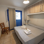 Schlafzimmer mit Doppelbett, weißer Bettwäsche, Holzstuhl und Fenster.