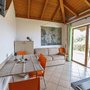Helles Wohnzimmer mit Tisch, orangefarbenen Stühlen, Sofa und großer Glastür zur Terrasse.