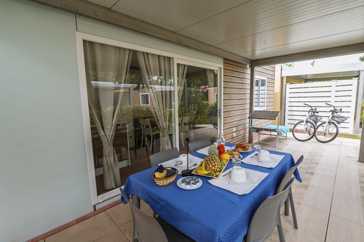 Gedeckter Tisch mit Frühstück auf einer Terrasse, zwei Fahrräder im Hintergrund.