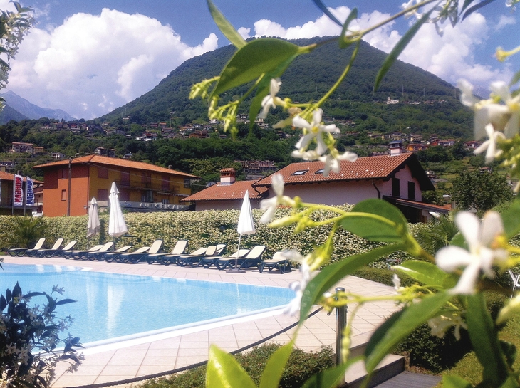 Berglandschaft mit blühenden Pflanzen und einem Pool im Vordergrund.