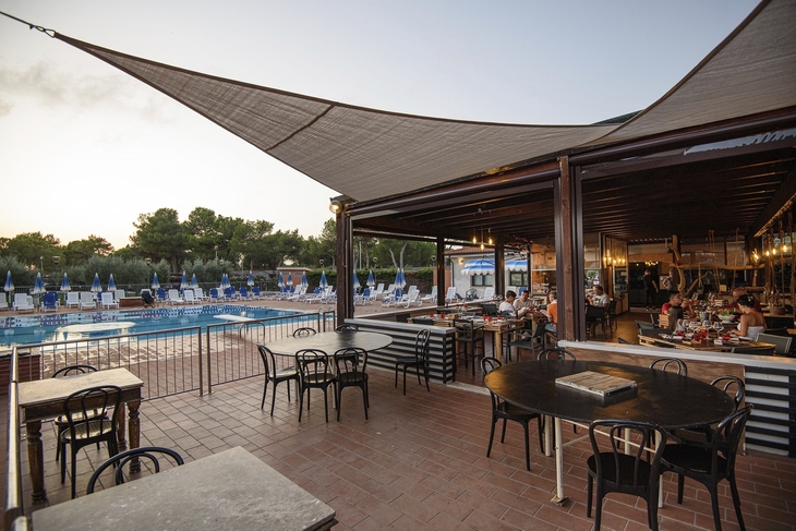 Bar mit Sitzbereich neben einem Pool bei Sonnenuntergang.